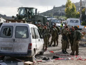 This picture taken on November 26, 2018 shows Israeli soldiers standing by a damaged car at the scene of an attack where a Palestinian man rammed a vehicle into three Israeli soldiers. (AFP/File)