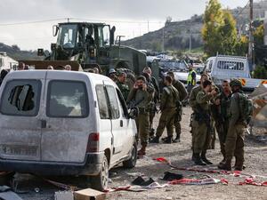 This picture taken on November 26, 2018 shows Israeli soldiers standing by a damaged car at the scene of an attack where a Palestinian man rammed a vehicle into three Israeli soldiers. (AFP/File)