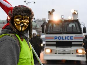 A masked protestor stands in front of a police vehicle in Paris on January 5, 2019, during a rally by yellow vest "Gilets Jaunes" anti-government protestors. (Bertrand GUAY / AFP)