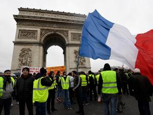 Protesters stand holding a French flag near the Arc de Triomphe on the Place de l'Etoile in Paris during an anti-government demonstration. (AFP)
