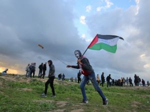 A Palestinian protester wearing a Guy Fawkes mask while holding a Palestinian flag and hurling a slingshot following a demonstration at Gaza border with Israel. (SAID KHATIB / AFP)