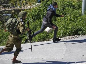 An Israeli soldier chases a Palestinian protester during clashes following a demonstration against Jewish settlements west of Ramallah, on March 8, 2019. (ABBAS MOMANI / AFP)