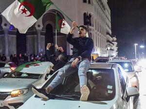 An Algerian youth waves a national flag as he sits atop a car during a demonstration in the centre of the capital Algiers on March 11, 2019, after President Abdelaziz Bouteflika announced his withdrawal. (AFP)