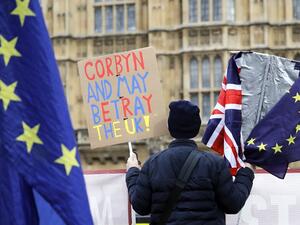An anti-Brexit activist holds a placard and Union and EU flags as they demonstrate outside the Houses of Parliament in London on March 27, 2019. (Tolga AKMEN/ AFP)