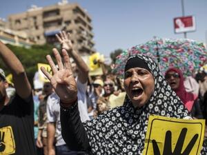 Supporters of ousted Egyptian president Mohamed Morsi raise posters with the four-finger symbol during a demonstration against the military-backed government in the Egyptian capital, Cairo.(AFP PHOTO/MAHMOUD KHALED)