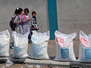 Palestinian school girls walk past sacks of flour outside a UN compound at the Rafah refugee camp in the southern Gaza Strip. (AFP/ File)
