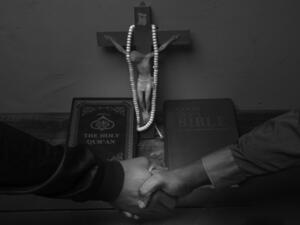 Christian and Muslim handshake over a Holy Bible and Quran. (Shutterstock)