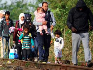 Migrant families walk along a railway track near the border village Roszke, at the Hungarian-Serbian border on August 25, 2015. (AFP/Attila Kisbenedek)
