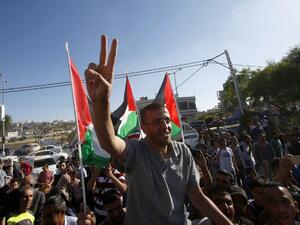 Mohammed al-Qiq flashes a peace sign as he arrives back to his village in the West Bank. (AFP/Hazem Bader)