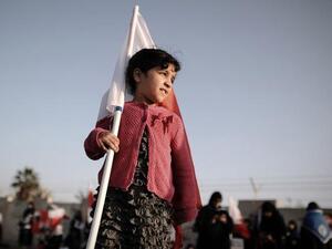 A young Bahraini girl holds a national flag during an anti-government rally in the village of Diraz, west of Manama, on January 17, 2014. [AFP]