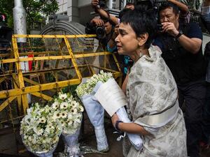 A woman leaves a floral arrangement on a road block leading to a cafe in Dhaka that was the site of a bloody siege. (AFP/File)
