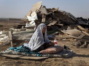 A Bedouin woman sits in front of a razed home. (AFP/File)