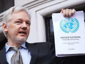  WikiLeaks founder Julian Assange holds a copy of the UN report condemning his 'arbitary detention' as he addresses reporters from the Ecuadorian embassy in London, on February 5, 2016. (AFP/File)