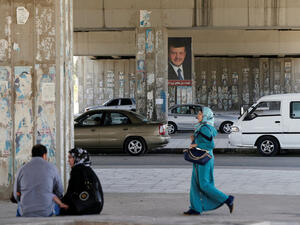 A woman walks past a poster of Jordan's King Abdullah. (AFP/File)
