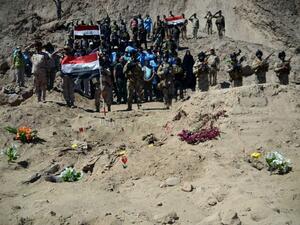 Iraqi soldiers stand next to a mass grave in Tikrmt. (AFP/File)