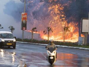 Israelis drive past a fire raging through the northern Israeli port city of Haifa on November 25, 2016. (AFP/File)