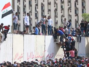 Iraqi protesters climb over a concrete wall surrounding the parliament after breaking into Baghdad. (AFP/File) Iraqi protesters climb over a concrete wall surrounding the parliament after breaking into Baghdad. (AFP/File)