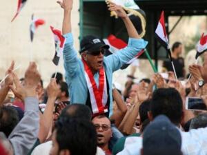 An Iraqi man chants slogans as other wave their national flag during a demonstration against corruption. (AFP/File)