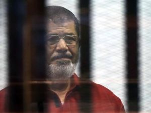 Egypt's ousted President Mohamed Morsi, wearing a red uniform, stands behind bars during his trial. (AFP/File)