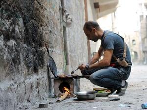 A rebel fighter cooks food on a make-shift stove in Syria's Aleppo. (AFP/File)