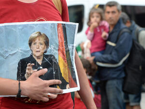 A refugee holds a picture of German Chancellor Angela Merkel as refugees arrive at the main station of Munich. (AFP/File)