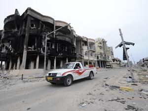 Libyans drive through a destroyed neighborhood in Sirte in 2011. (AFP/File)