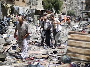 Syrians walk amid the rubble following air strikes by Syrian government forces on a marketplace. (AFP/File)