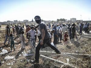 A man stands on the downed border fence. Turkish security personnel have worked to prohibit the Kurds from entering Syria. (AFP/Bulent Kilic)
