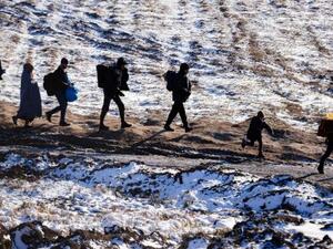 Migrants and refugees walk along snow-covered fields after crossing the Macedonian border into Serbia. (AFP/File)