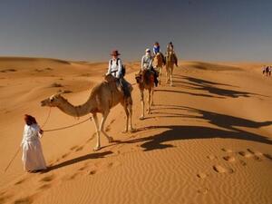Tourists take a camel ride to visit the Bedouin village at Wahiba Sands. (Oman Tourism Ministry)