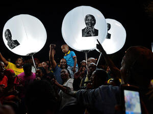 People hold up balloon lamps bearing the image of late former South African president Nelson Mandela during a commemorative ceremony outside the late leader's former home. [AFP]