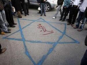 فلسطينيون في رام الله يتحلقون حول رسم على الارض لعلم اسرائيلي كتب في وسطه اسم قناة الجزيرة