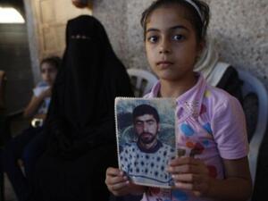 طفلة فلسطينية تحمل صورها لوالدها المعتقل في سجون الإحتلال الإسرائيلية