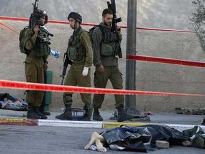 شهيد فلسطيني ملقى على الارض بجانب جنود الاحتلال/ ارشيفية