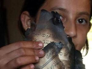 ليندا بيدا تحمل صفحات من المصحف بعد احراقه في منزل والديها في قرية جيوس في شمال الضفة الغربية
