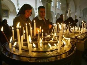 شخصان يوقدان الشموع في كنيسة المهد في بيت لحم
