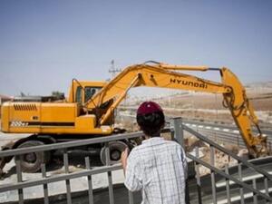 صبي من المستوطنين يراقب الية حفر في احد المواقع الاستيطانية