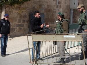 A Palestinian man has his identity checked by Israeli border police patrolling the streets of the West Bank city of Hebron on January 5, 2016. (AFP/Menahem Kahana)