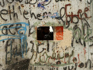 A member of Israeli security forces aims through a hole in the iron gate along the Israeli controversial separation barrier in the West Bank town of Bethlehem. (AFP/File)