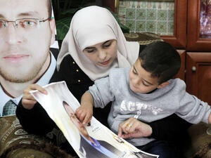 Fayha Shalash, the wife of Palestinian journalist Muhammed al-Qiq, sits with her son at her home in the West Bank village of Dura on January 20, 2016.