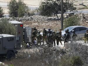 Israeli soldiers surround the body of a suspected Palestinian man who was reportedly shot dead by Israeli troops at the entrance to the West Bank village of Silwad on August 26, 2016. (AFP/Abbas Momani)