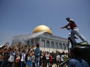 A man sprays water to cool down Palestinian children gathering in front of the Dome of the Rock in Jerusalem's Al-Aqsa mosque compound before Friday prayers during Ramadan on June 24, 2016. (AFP/Ahmad Gharabli)