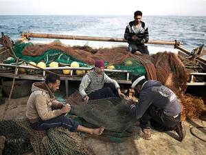 Palestinian fishermen fix nets on a boat as they start fishing off the coast of the Gaza Strip on April 3, 2016. (AFP/File)