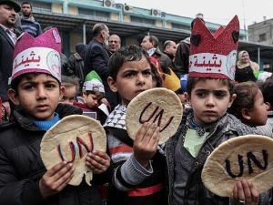 Palestinian children hold bread patties during a protest against aid cuts, outside the United Nations' offices in Khan Yunis in the southern Gaza Strip on January 28, 2018. (Said Khatib/AFP)
