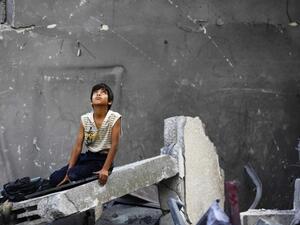 A Palestinian boy sits on the rubble of a destroyed building following an Israeli air strike in the center of Gaza City on July 22, 2014. (AFP/file)