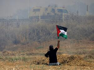 This file photo taken on May 19, 2017 shows Palestinian demonstrator Ibrahim Abu Thurayeh waving a Palestinian flag during clashes with Israeli soldiers (Mohammed Abed/AFP)