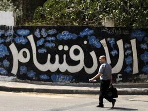 A Palestinian man walks past a graffiti reading in Arabic ''Division'' in Gaza City, on September 17, 2017, after Hamas announced it had agreed to steps toward resolving a decade-long split with the Fatah movement and was ready to hold elections (Mahmud Hams/AFP)