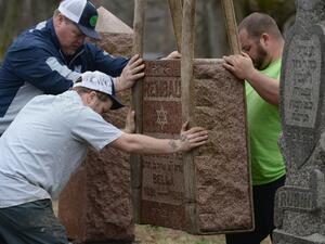 Volunteers from a local monument company help to reset vandalized headstones at Chesed Shel Emeth Cemetery on February 22, 2017 in University City, Missouri [AFP/Michael Thomas]