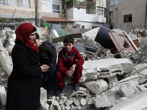 Palestinian children and their mother sit on the rubble of their house that was demolished by Israeli army bulldozers in the east Jerusalem neighborhood of Beit Hanina on February 22, 2017. (AFP/Ahmad Gharabli)