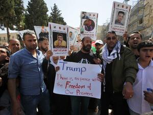 Palestinian protesters shout slogans and hold placards outside the Church of the Nativity in Bethlehem during a demonstration in support of prisoners refusing food in Israeli jails, on May 23, 2017, during a visit of the US president to the West Bank town. (AFP/Hazem Bader)